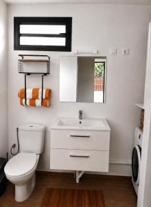 a white bathroom with a toilet and a sink at Au Petit Bungalow - Air conditionned & Mountain view in Moorea +1 photo