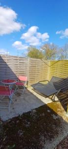 a patio with two chairs and a table in front of a fence at studio love et detente in Saint-Philbert-sur-Risle