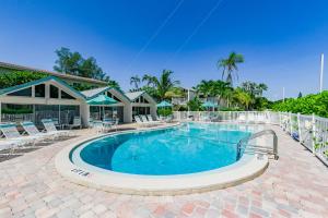 a large swimming pool with chairs and a house at Coconuts Beachfront #112 in Holmes Beach