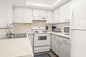 a kitchen with white cabinets and a white refrigerator at Coconuts Poolside #115 in Holmes Beach