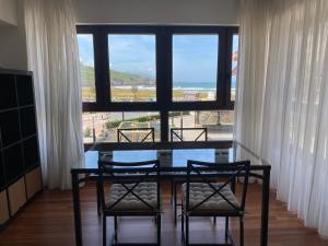 a dining room with a glass table and four chairs at La Arena Beach sunset in Ciérvana