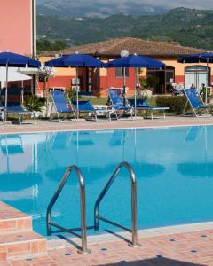 a large swimming pool with blue chairs and umbrellas at Villa Cilento Parking e Sosta Camper in Capaccio-Paestum