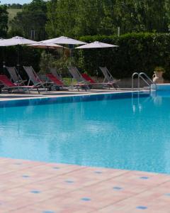a swimming pool with chairs and umbrellas at Villa Cilento Parking e Sosta Camper in Capaccio-Paestum +1 photo
