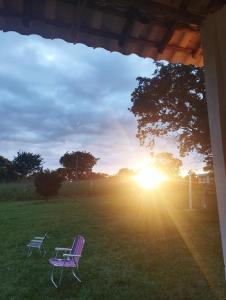 a purple chair and a bench in a field with the sunset at Sítio Azevedo in Buenópolis