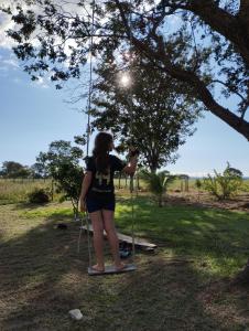 a woman standing on a swing under a tree at Sítio Azevedo in Buenópolis