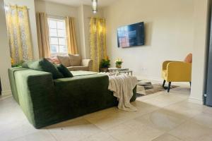 a living room with a green couch and a tv at Casa Amarilla St Michael in Bridgetown