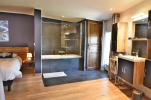 a bedroom with a bed and a tub and a sink at Suite parentale avec un petit salon in Homps +8 photos