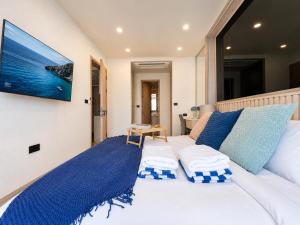 a white bed with blue pillows and a tv on a wall at Cozy 1 BR Bangtao Beach in Laguna Phuket