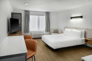 a hotel room with a white bed and a tv at StudioRes by Marriott Columbia Harbison in Columbia