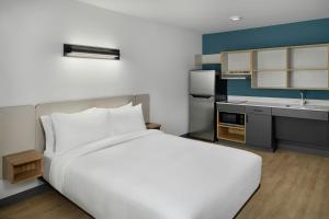 a bedroom with a large white bed and a kitchen at StudioRes by Marriott Columbia Harbison in Columbia