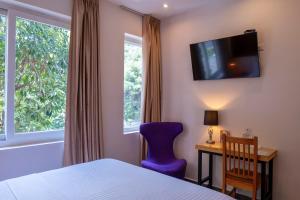 a bedroom with a bed and a blue chair and a window at Kaleo Hotel Boutique in San Salvador
