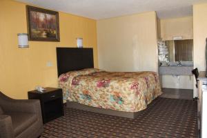 a hotel room with a bed and a chair at Charles Wesley Motor Lodge Downtown Broken Bow- Hochatown in Broken Bow +29 photos