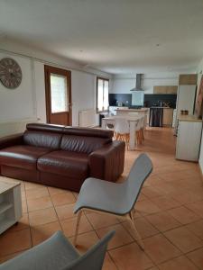 a living room with a brown leather couch and a kitchen at Le Petit Moulin de Verberie in Verberie