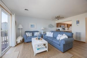a living room with two blue couches and a table at 4203 - Here Comes the Sun in Duck