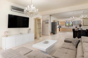 a living room with a couch and a tv at Sunny Palm Villa in Ialysos