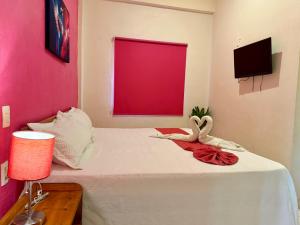 a bedroom with a white bed with a red window at Hotel Barranquilla in Campeche
