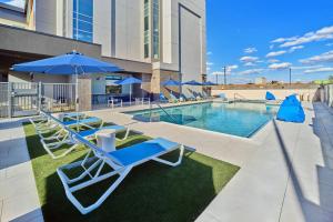a pool with lounge chairs and umbrellas at a hotel at SpringHill Suites by Marriott Phoenix Gilbert in Gilbert