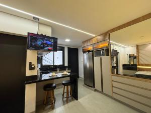a room with a kitchen with a bar and a refrigerator at Haven Residence in Uberlândia