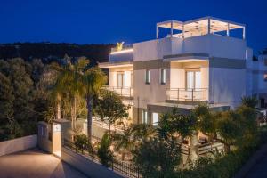 a large white house with palm trees in front of it at Sunny Palm Villa in Ialysos
