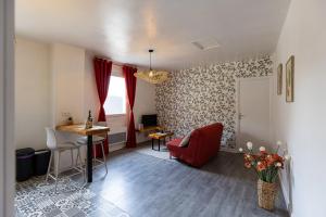 a living room with a red chair and a table at Le Cadélac - appartement centre ville cosy in Loudéac