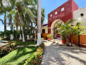 a red building with palm trees and flowers in a yard at Hotel Barranquilla in Campeche