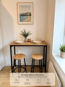 a table with two stools and plates on it at LE 23 ter in Jarny