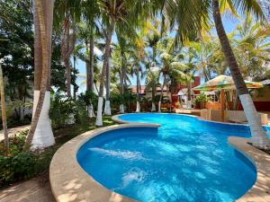 a swimming pool with palm trees in a resort at Hotel Barranquilla in Campeche