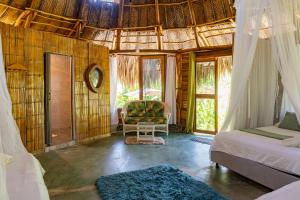 a room with two beds and a chair and windows at Magic Green Dentro del Parque Tayrona in El Zaino