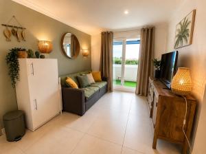 a living room with a couch and a tv at Charmant appartement en front de mer avec piscine in Lacanau-Océan