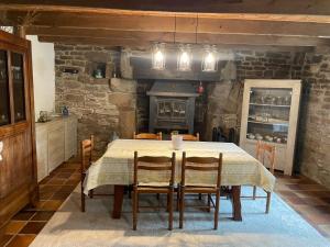 a dining room with a table with chairs and a fireplace at Le Breizh des Bois in Le Faouët