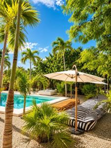 a swimming pool with a patio umbrella and palm trees at Villa Luxauthentika Tulum in Tulum