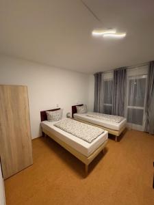 two beds in a room with two windows at Pension Reiter in Berlin
