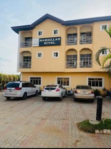 a hotel with cars parked in front of it at Mambillah Hotel Ikorodu in Ikorodu