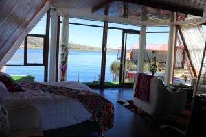 a bedroom with a bed and a view of the water at Titicaca Mia Lodge Perú in Puno