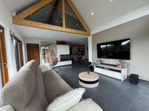 a living room with a couch and a tv at Harizou - Chalet & Piscine Intérieure in Saint-Pierre-la-Vieille