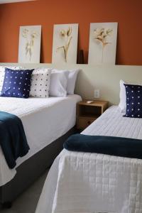 two beds in a room with paintings on the wall at Casinha de Aldeia in Aldeia Velha