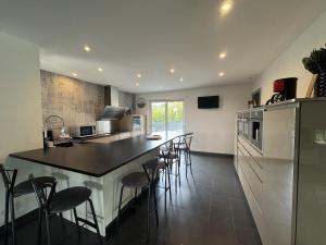 a kitchen with a large island in a kitchen with bar stools at Harizou - Chalet & Piscine Intérieure in Saint-Pierre-la-Vieille