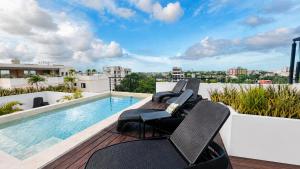 ein Balkon mit Stühlen und ein Swimmingpool auf einem Gebäude in der Unterkunft Live Coco Suites - Hotel Boutique & Rooftop in Playa del Carmen