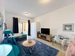 a living room with a couch and a tv at Royal Breeze Executive Studio in Ras al Khaimah
