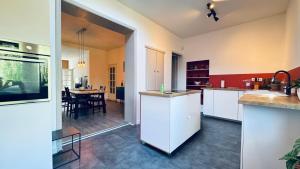 a kitchen with white cabinets and a dining room at Le refuge de Boncelles in Seraing