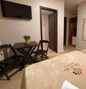 a living room with a table and chairs and a television at Pousada Folhas de Outono in Canela