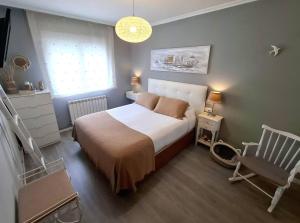 a small bedroom with a bed and a chair at Dúplex 4 dormitorios Playa Foz in Foz