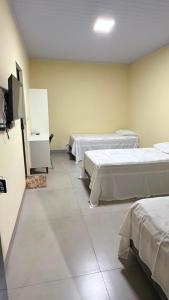a room with three beds and a flat screen tv at Hotel Rocha in Novo Acordo