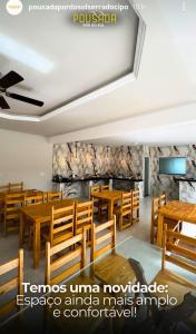 a restaurant with wooden tables and wooden chairs at Pousada por do soll in Serra do Cipo