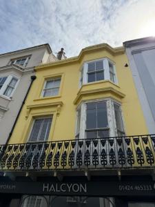 a yellow house with a balcony on a street at Captain Normans Sea view in Hollington