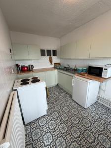a kitchen with white appliances and a tile floor at Captain Normans Sea view in Hollington +21 photos
