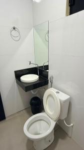 a bathroom with a white toilet and a sink at Hotel Rocha in Novo Acordo