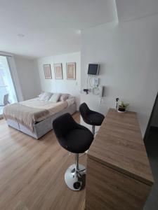a bedroom with a bed and two chairs in it at Cozy studio apartment with a privileged view in Manizales