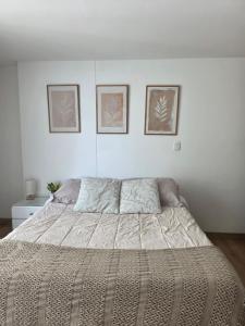 a bed in a bedroom with three pictures on the wall at Cozy studio apartment with a privileged view in Manizales