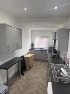 eine Küche mit weißen Schränken und einer schwarzen Arbeitsplatte in der Unterkunft PLUS Properties Dike 1 in Stoke on Trent + 10 Fotos